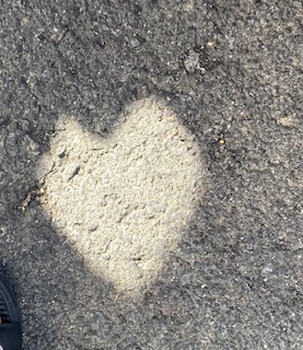 Photo of dark asphalt that is significantly lighter in the shape of a heart in one spot